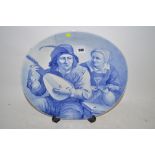 19th century delft blue and white charger depicting a man playing a lute in a tavern.