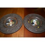 Two hand painted porcelain plates portraying a man and a woman mounted in metal dishes.