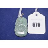 A Chinese carved green hardstone pendant with white metal mount stamped 18KGP.