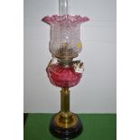 Cranberry glass and brass corinthium column oil lamp fitted for electricity, height 69cms.