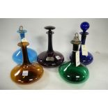 Five Georgian coloured glass decanters.