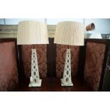 A pair of modern white painted wooden pylon style table lamps with raffia shades.