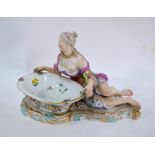 A Meissen porcelain posy vase modelled as a reclining semi-nude female, holding a basket of flowers,