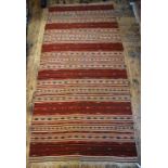 An antique Caucasian kelim, the multi-coloured design in horizontal stripes on ivory and red ground,