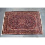 An antique Persian Kashan rug, the traditional floral design on red-blue ground,