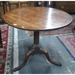 An 18th century circular tilt top oak tripod table with turned support to pad foot legs,