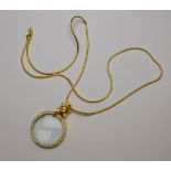 A magnifying glass pendant surmounted by