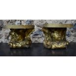A pair of carved giltwood wall brackets in the form of a cherub head beneath shaped platforms,