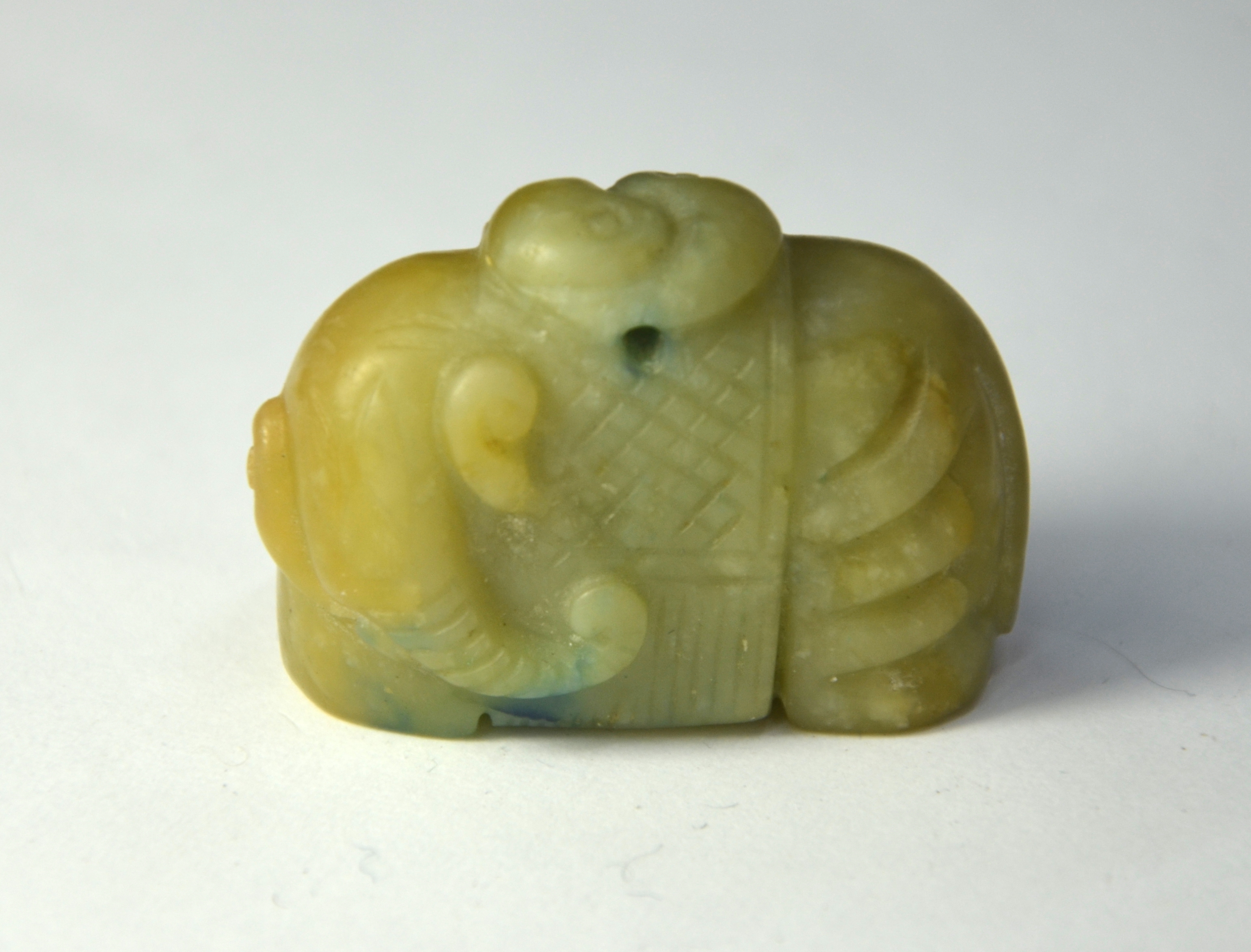 A mottled green stone figure of a standing elephant looking to the left and wearing a long howdah - Image 2 of 4