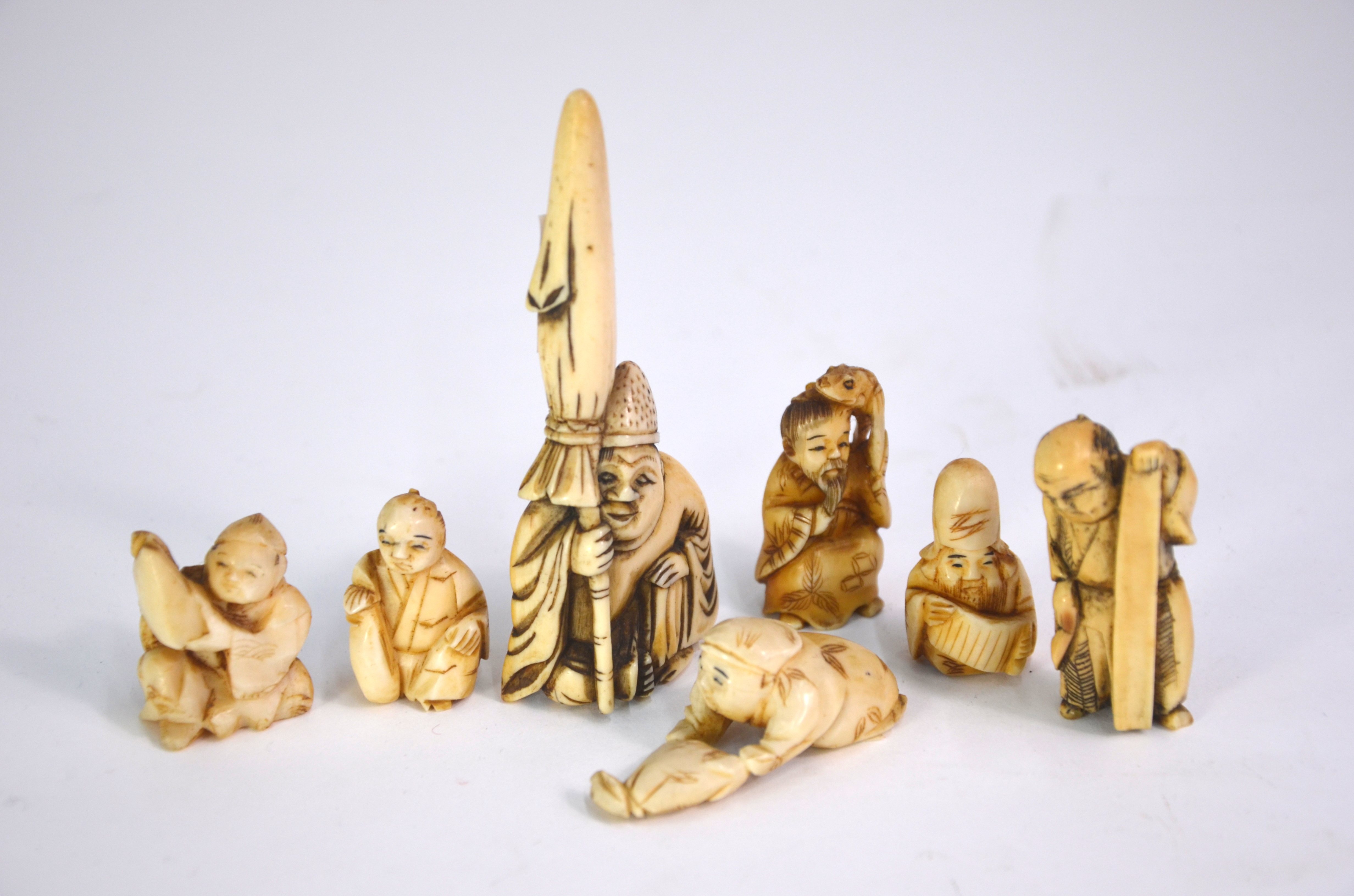 Seven ivory netsuke, including: one of Jurojin holding a makemono; and one of Gama Sennin holding