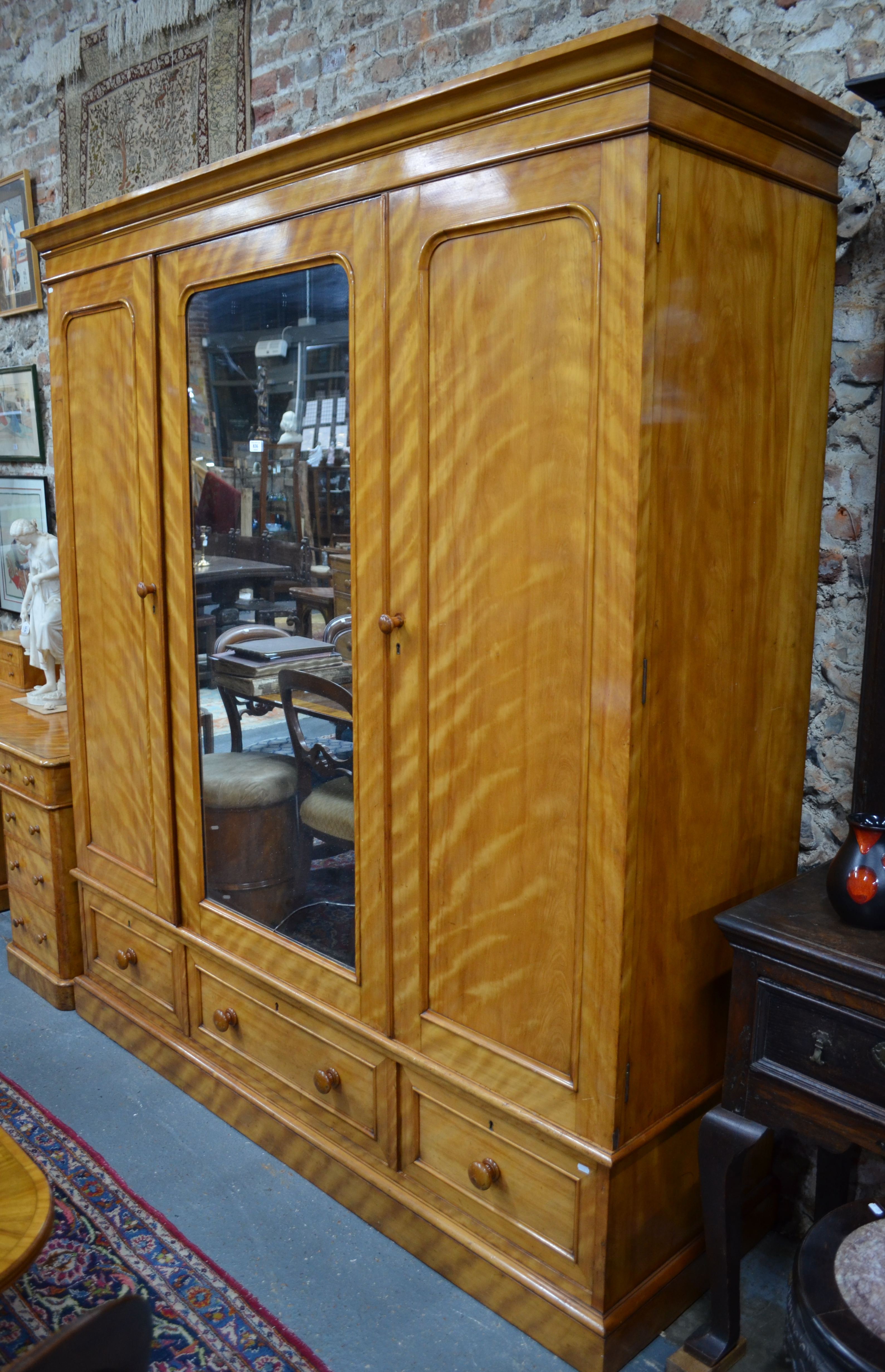 Heal & Son, London, a Victorian satin-birch triple wardrobe/compactum, the centre door with mirrored