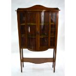 An Edwardian inlaid red walnut bowfront display cabinet with shaped undertier, raised on spade