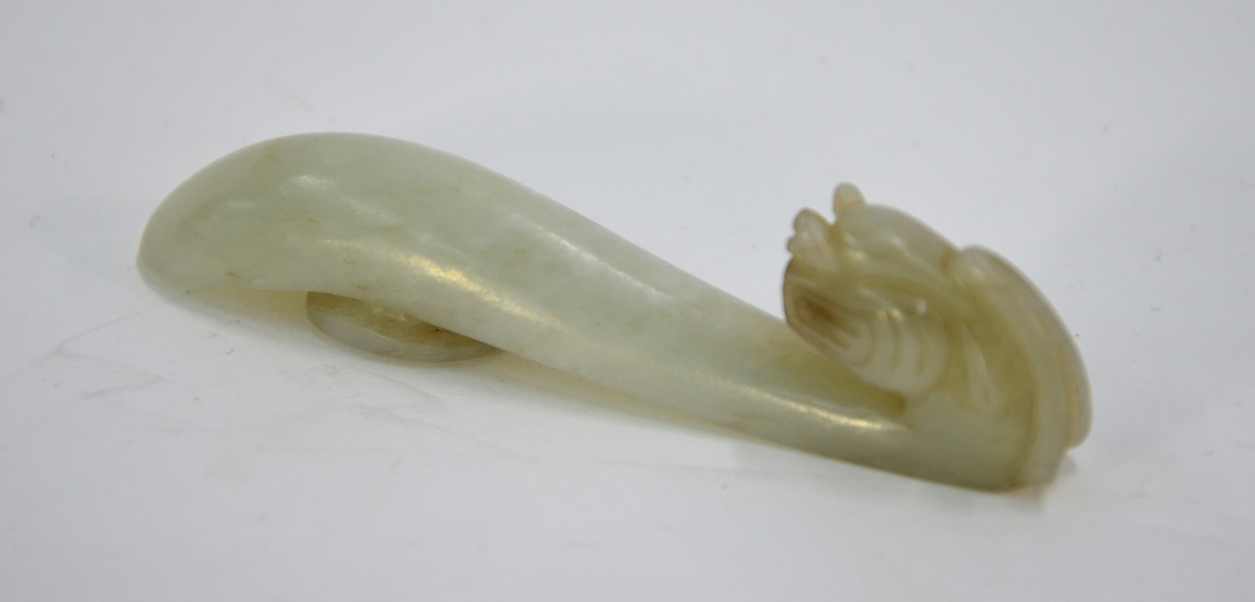 A mottled jade belt hook with mythological animal head and oval boss; 8.5 cm long, Qing Dynasty or