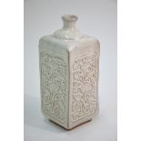 A cream-grey bottle vase of square section; decorated on each rectangular panel with carved floral