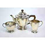 A three-piece silver tea service with floral-cast rim and moulded foot, composite handle and finial,