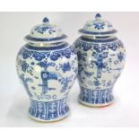 A pair of Chinese blue and white vases; each one with a domed cover and knop finial, decorated