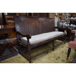 An 18th century jointed oak settle, the four arched panel back over swept arms and a rope sprung