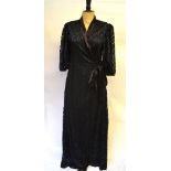 An unusual 1930s black silk wrap-style evening dress with overall cut-out work and silk satin trim