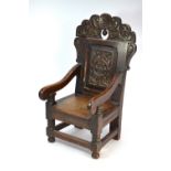 An antique children's oak Wainscot chair, the carved crest rail over a panelled back centred with