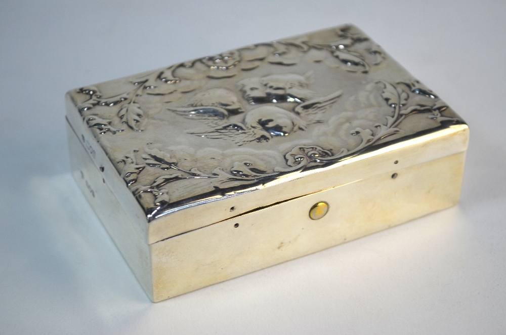 A late Victorian silver stamp-box, embossed with winged cherub heads, ebony lining with curved