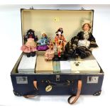 A collection of costume dolls in suitcase