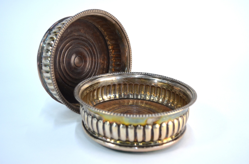 A pair of George III half-reeded silver bottle coaster with egg and dart moulded rims and turned