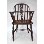 A 19th century elm seat Windsor elbow chair, raised on ring turned legs