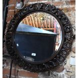 A carved and pierced circular oak mirror with bevelled edged plate, circa 1920's, 70 cm diam