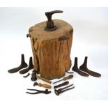 An antique set of cast iron cobbler's lasts, mounted on a heavy tree stump, to/w tools