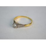 A single stone brilliant cut diamond ring having diamond set shoulders, yellow and white metal