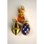 Three various charms including green and yellow enamel egg, blue enamel and white paste egg, and