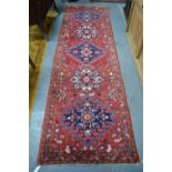 A Persian Heriz runner, the diamond pole design on red ground, 333 x 101 cm  - good even pile