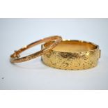 A 9ct hollow gold engraved hinged bangle, 6.4g, to/w a 9ct gold metal core broad example (2)