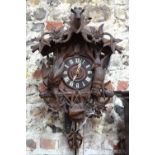 A late 19th century Black Forest cuckoo clock, the case decorated with carved game and flower heads,