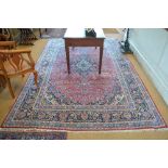 An old Persian Kashan carpet, the centre medallion in blue on a mid-red field, 330 x 216 cm wide