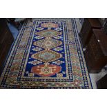 A handmade Kazak small carpet, the geometric design in dark blue on peach ground, 245 x 175 cm [