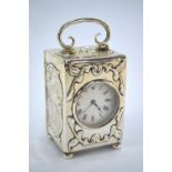 An Edwardian silver boudoir clock, embossed with winged cherub heads and scrolls, swing handle and