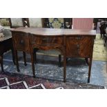 A slender George III satinwood and ebony inlaid mahogany sideboard of serpentine form, the frieze