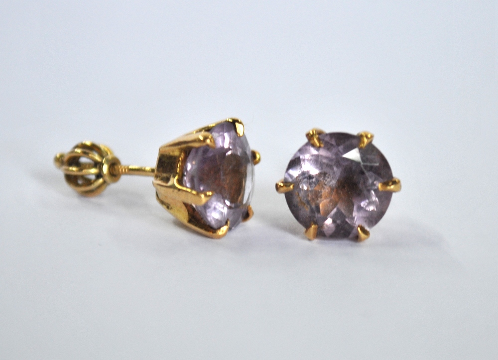 A pair of circular pale amethyst stud earrings, yellow metal claw set