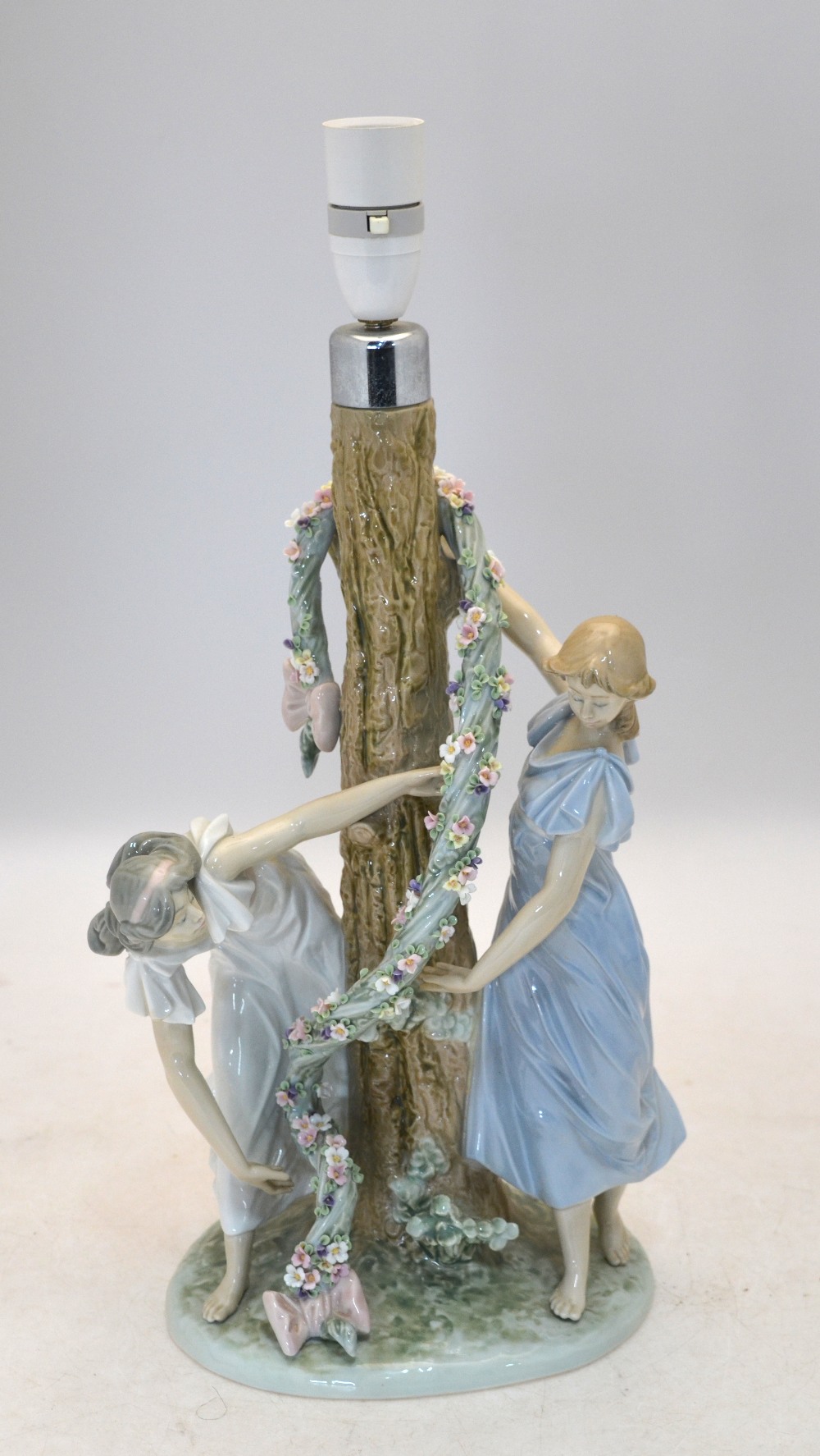 A Lladro lamp base with two maidens decorating a tree with a floral garland, 1607 impressed to base,