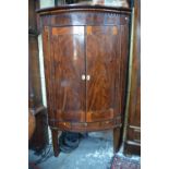 A George III satinwood and brass inlaid flame mahogany hanging corner cupboard, of bowfronted form