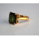 A single stone rectangular dark green tourmaline in yellow metal four claw setting