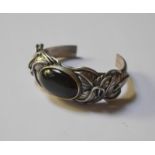 Carol Darby - a silver bangle of leaf scroll design, the centre set with oval labradorite, approx
