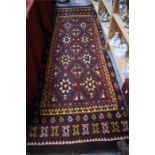 A Uzbek long rug circa 1900, the red-brown ground with stylised floral heads in yellow/red/ivory,