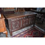 A late 17th/18th century carved oak coffer, the three plank moulded edge top over a carved triple