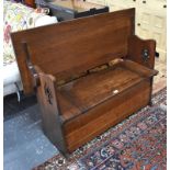 An Arts and Crafts period monks bench, the top hinging over to form a seatback, over a box seat with