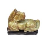 A large, mottled green figure of a recumbent horse, 26 cm long; with a fitted wood stand (2)