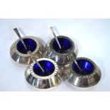 Stuart Devlin - a set of four circular silver open salts with crenelated rims and blue glass liners,