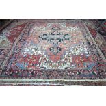 Persian Heriz carpet, large dark blue central medallion on red ground with stylized floral design