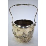 A white metal vase with hinged, looped handle, decorated on the exterior with a design of